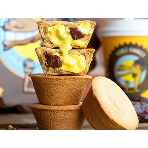 Two Camel Cookies cookie cups broken open to reveal a bright saffron-yellow filling studded with pieces of date, stacked above plain baked shells