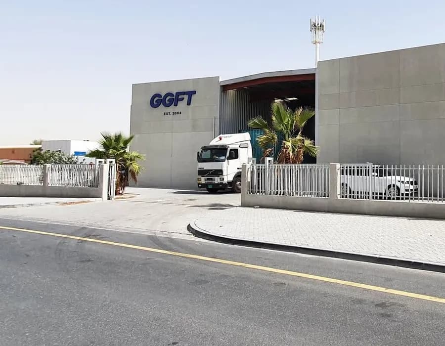 The GGFT warehouse in Dubai Investment Park 2, its facade signed GGFT, Est. 2004, with a truck at the loading bay